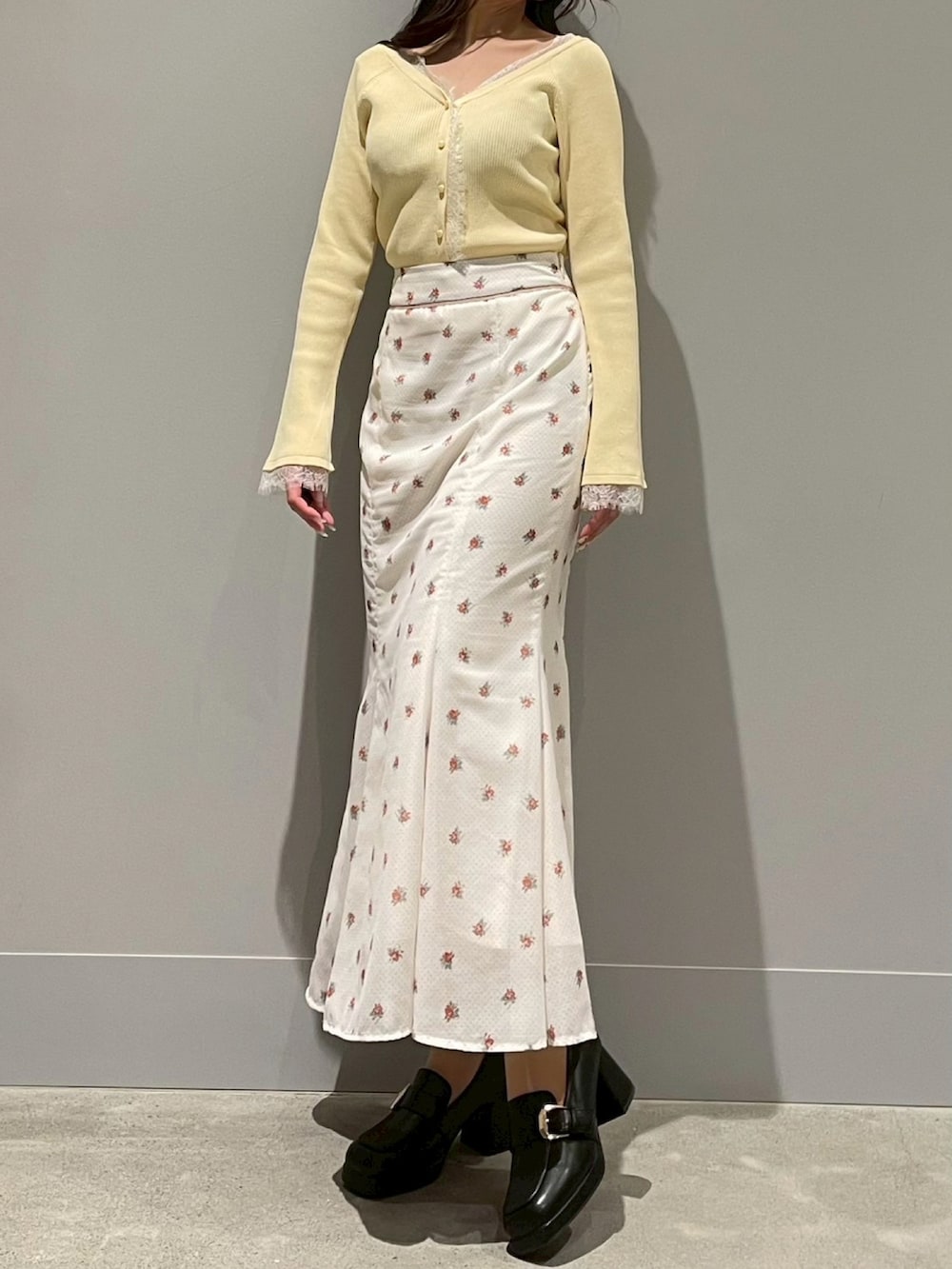 イエロー系のニット/セーター、ホワイト系のスカートを着用したレディースの春コーディネートの2枚目の写真