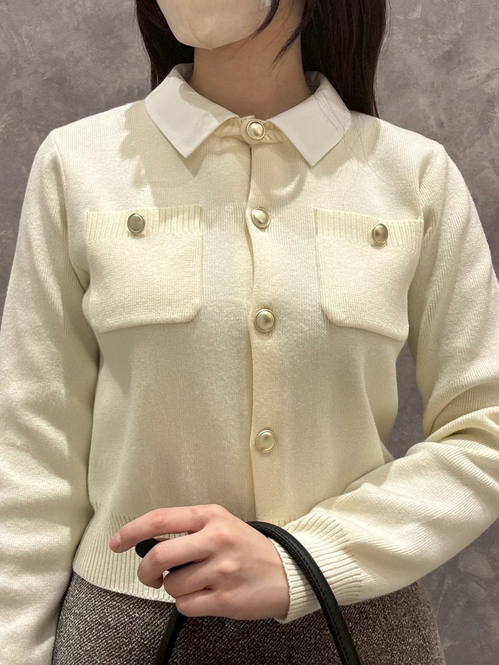 ホワイト系のカーディガン/ボレロ、ブラウン系のスカート、ベージュ系のショルダーバッグを着用したレディースの冬コーディネートの4枚目の写真