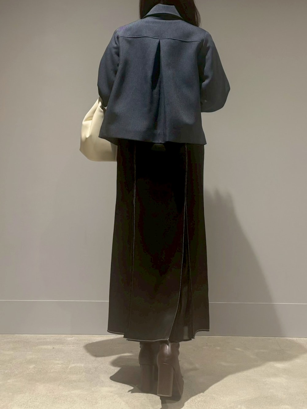 ブラック系のスカート、ベージュ系のブルゾン、ホワイト系のハンドバッグを着用したレディースの冬コーディネートの3枚目の写真