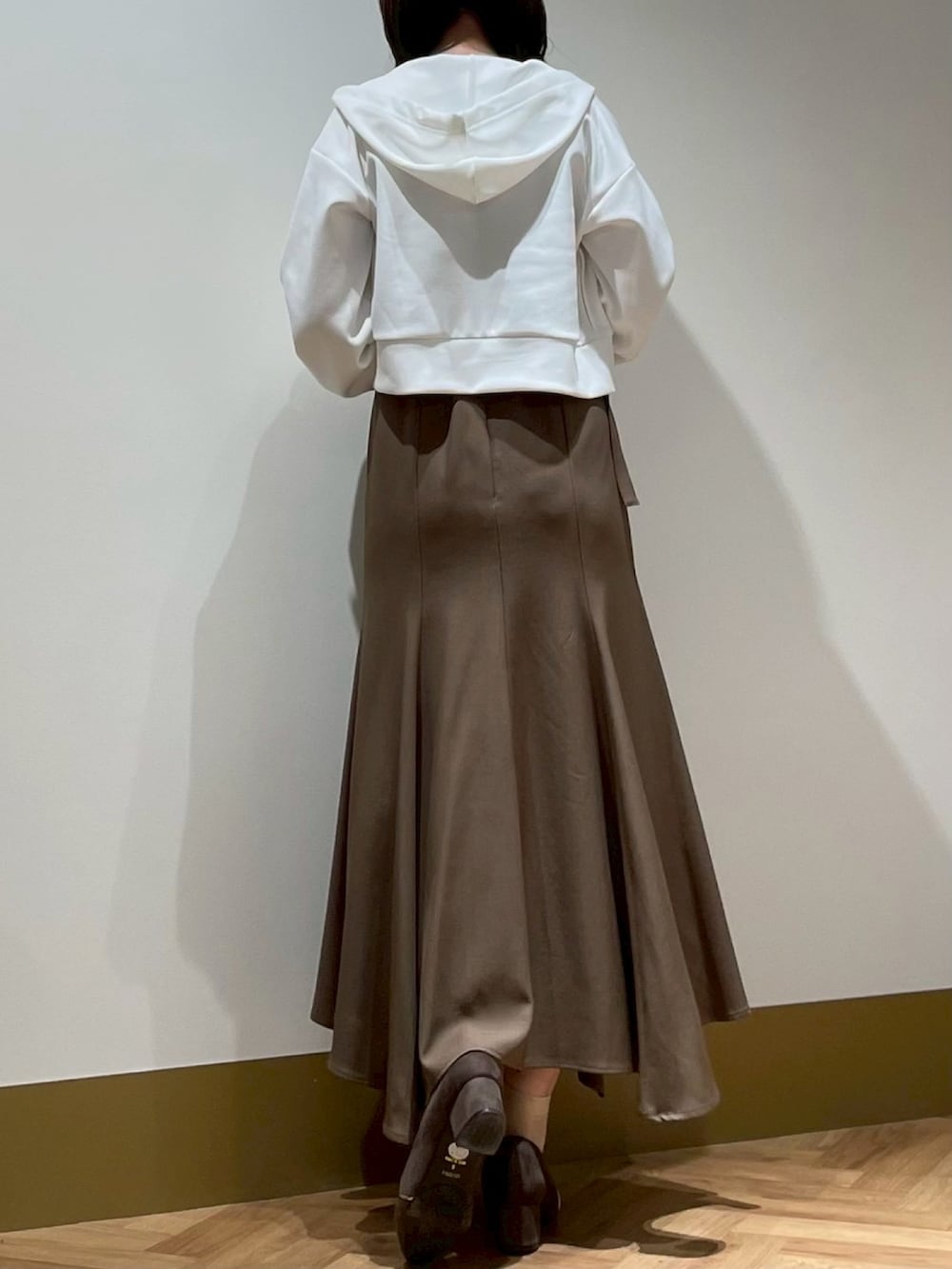 ブラウン系のジャンパースカート、ホワイト系のTシャツ/カットソー、ホワイト系のパーカーを着用したレディースの春コーディネートの3枚目の写真