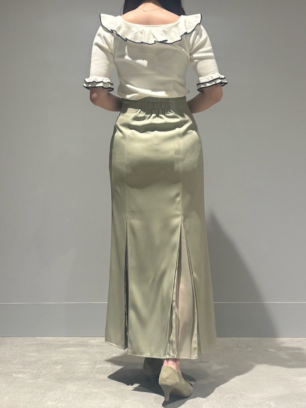 グリーン系のスカート、ホワイト系のニット/セーターを着用したレディースの春コーディネートの2枚目の写真