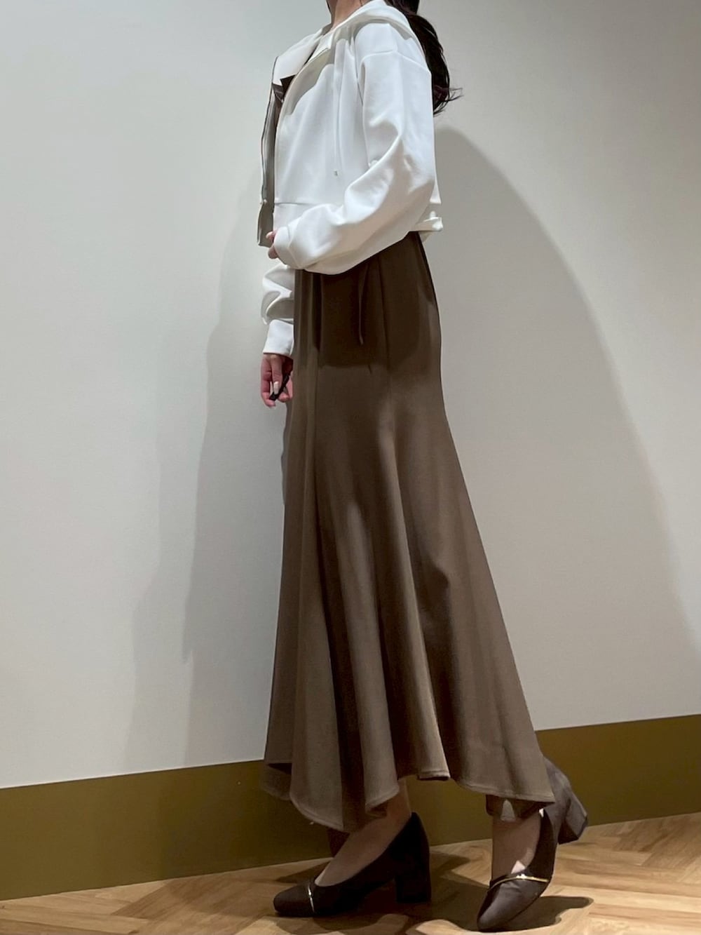 ブラウン系のジャンパースカート、ホワイト系のTシャツ/カットソー、ホワイト系のパーカーを着用したレディースの春コーディネートの2枚目の写真