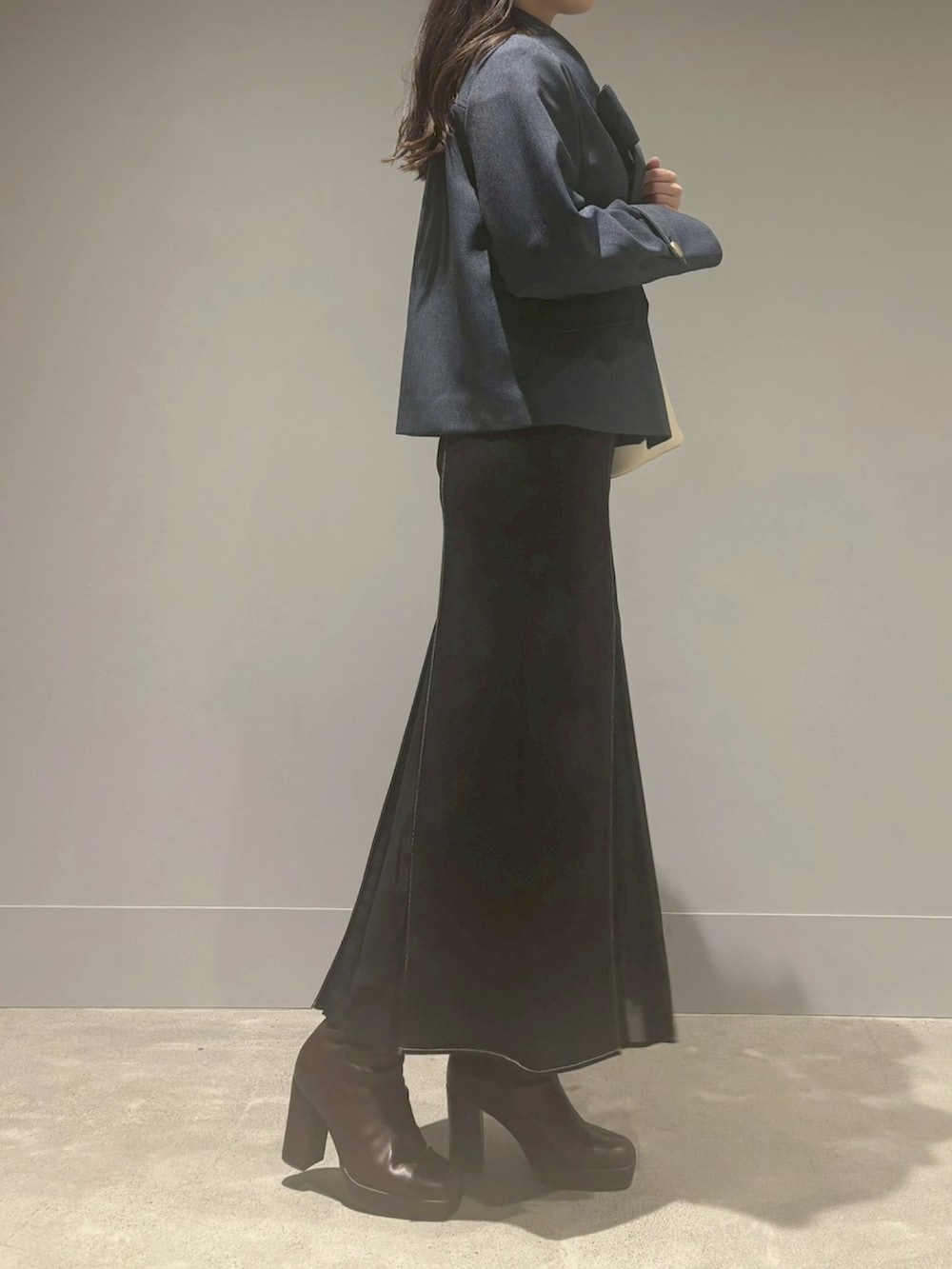 ブラック系のスカート、ベージュ系のブルゾン、ホワイト系のハンドバッグを着用したレディースの冬コーディネートの2枚目の写真