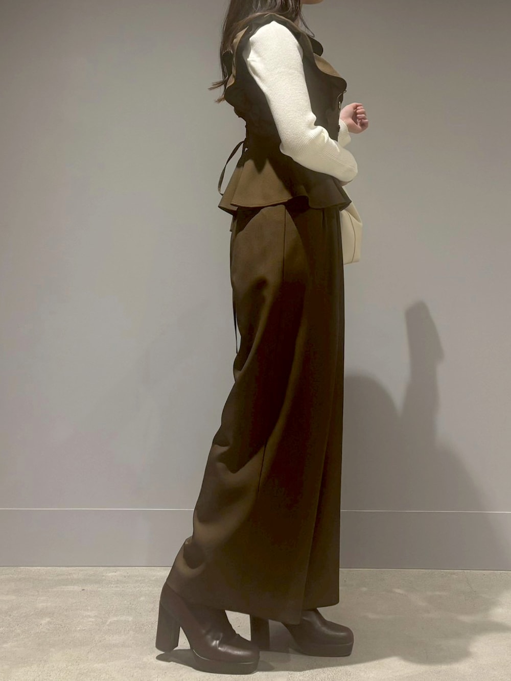 ブラウン系のつなぎ/オールインワン、ブラック系のハンドバッグ、ホワイト系のニット/セーターを着用したレディースの冬コーディネートの2枚目の写真