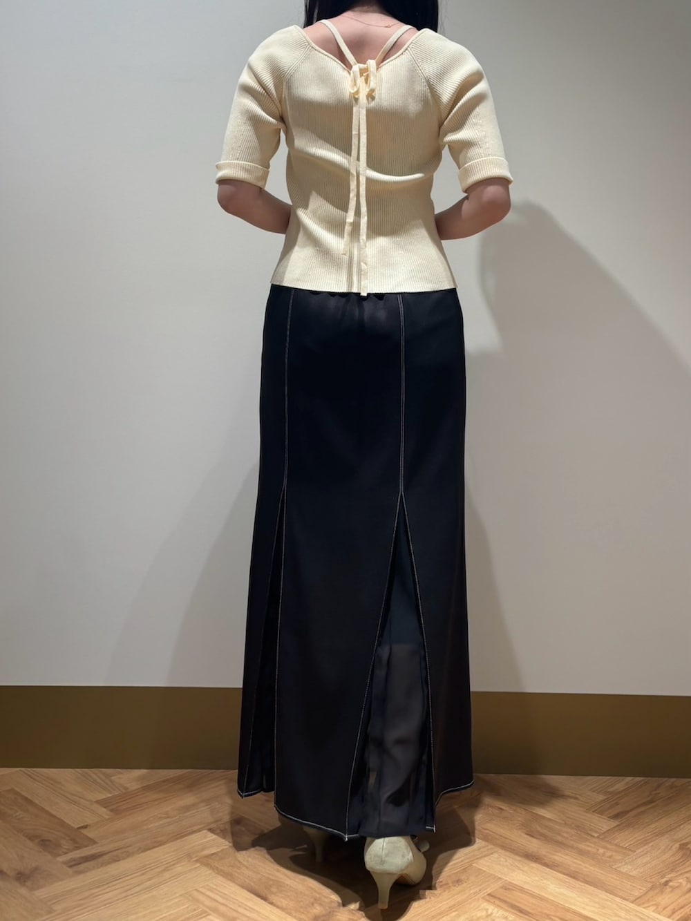 イエロー系のニット/セーター、ブラック系のスカートを着用したレディースの春コーディネートの3枚目の写真