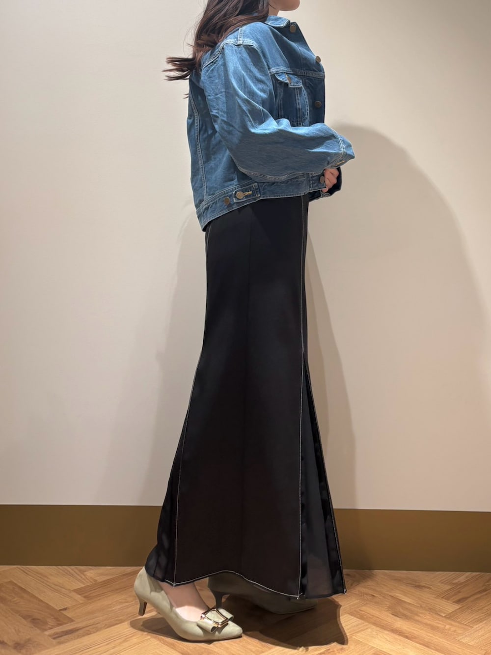 ブルー系のデニムジャケット、ブラック系のスカート、イエロー系のニット/セーターを着用したレディースの春コーディネートの2枚目の写真