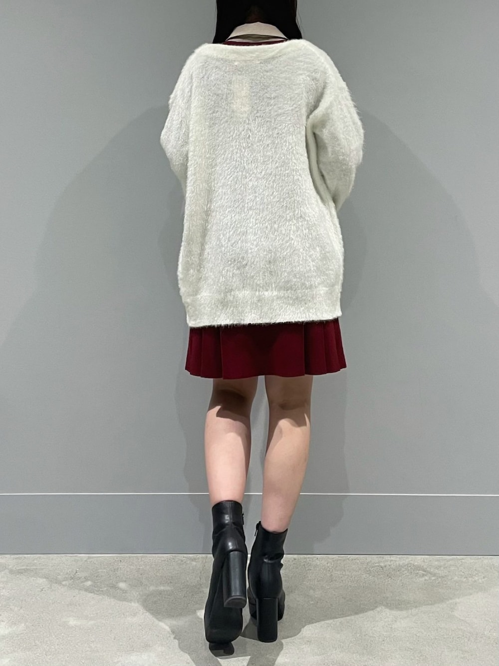 ホワイト系のカーディガン/ボレロ、レッド系のワンピース、ブラック系のブーツを着用したレディースの冬コーディネートの3枚目の写真