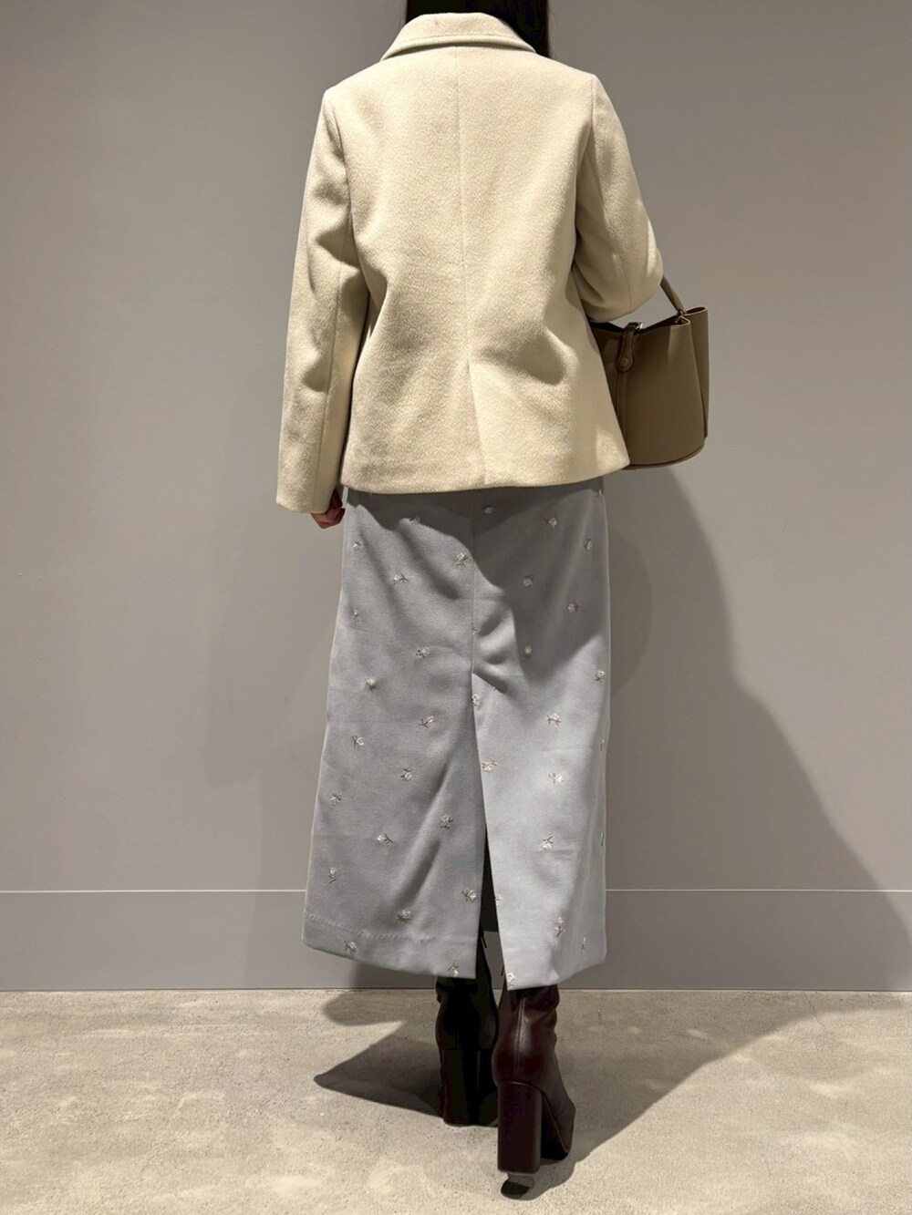 ブルー系のスカート、ベージュ系のハンドバッグ、ブラウン系のジャケット/アウターを着用したレディースの冬コーディネートの3枚目の写真