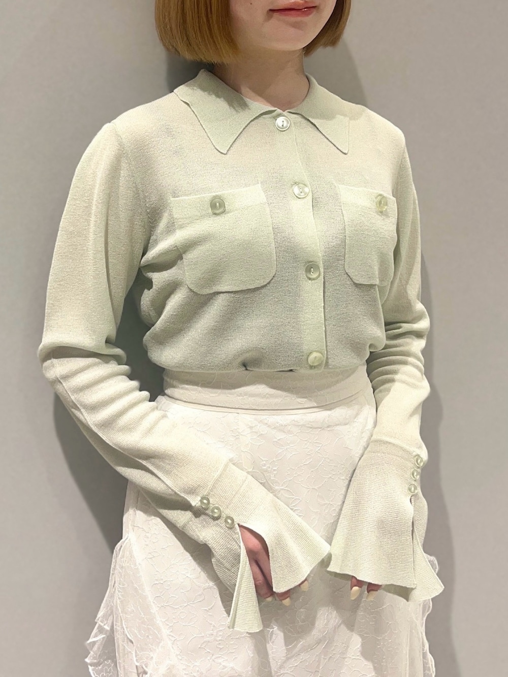 グリーン系のニット/セーター、ホワイト系のスカートを着用したレディースの春コーディネートの3枚目の写真