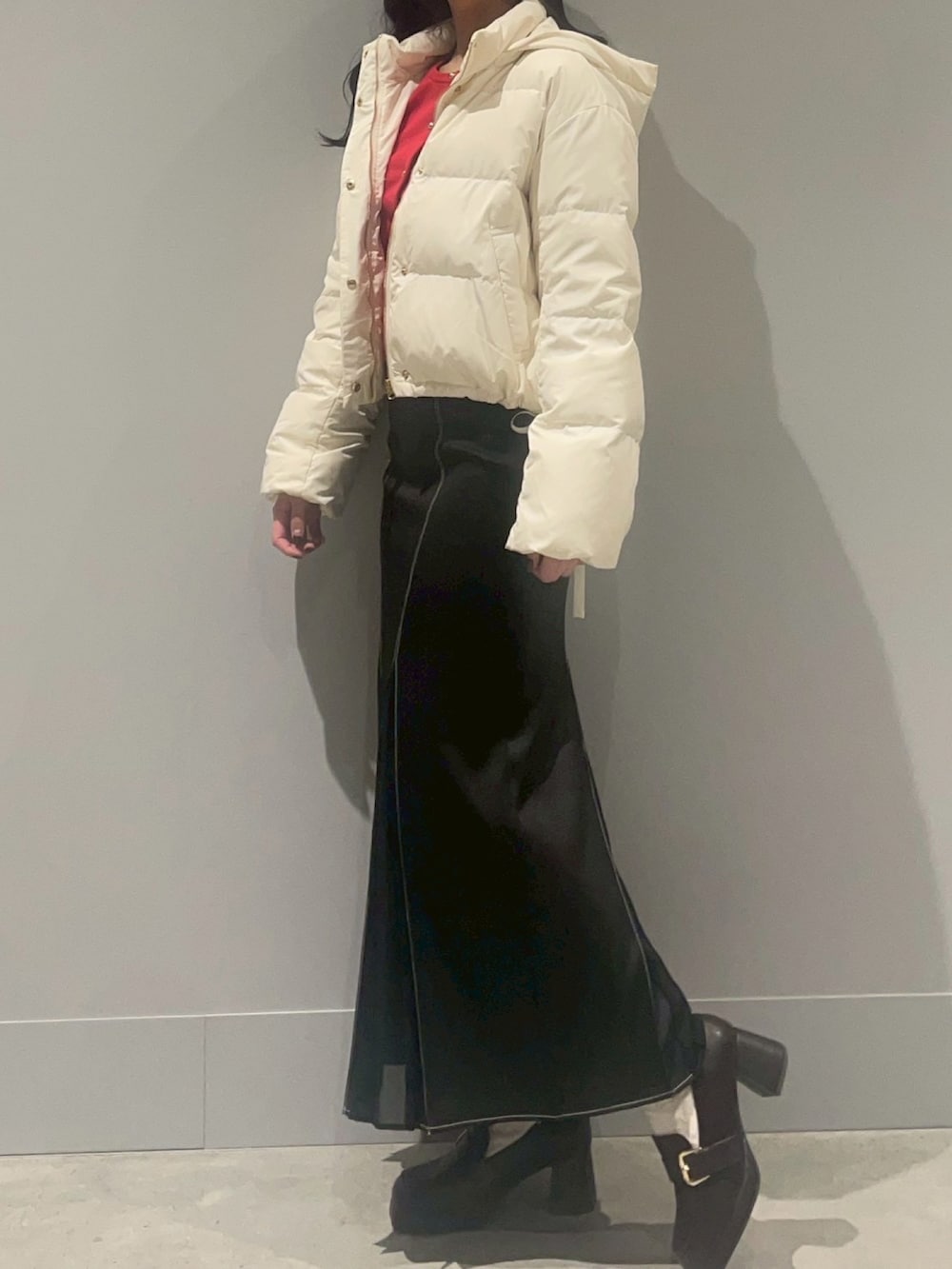 レッド系のカーディガン/ボレロ、ホワイト系のダウンジャケット/コート、ブラック系のスカートを着用したレディースの冬コーディネートの2枚目の写真