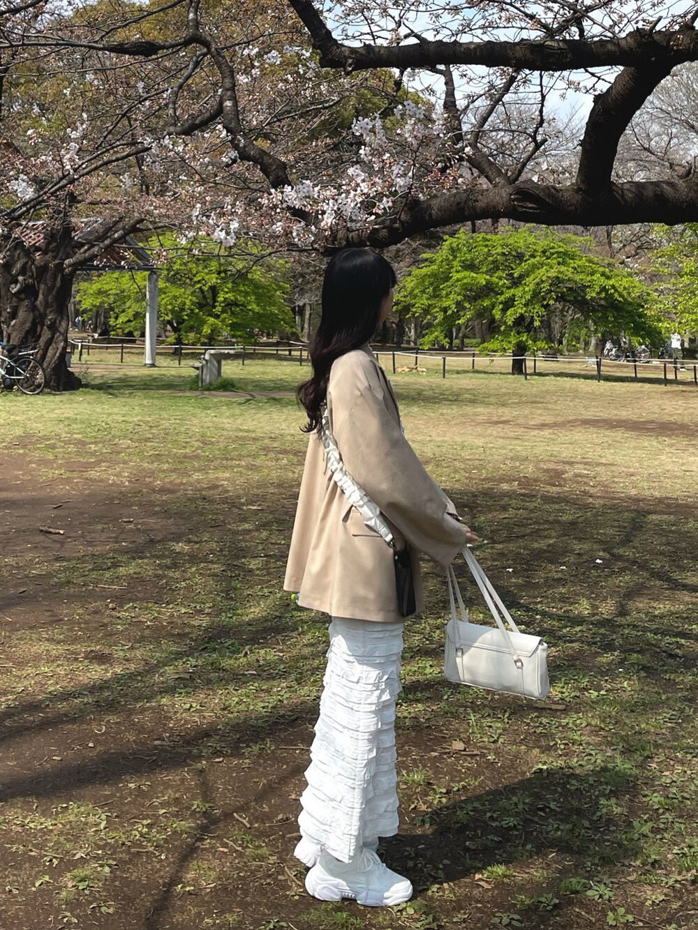 ベージュ系のテーラードジャケット、ホワイト系のスカート、ホワイト系のショルダーバッグを着用したレディースの春コーディネートの3枚目の写真