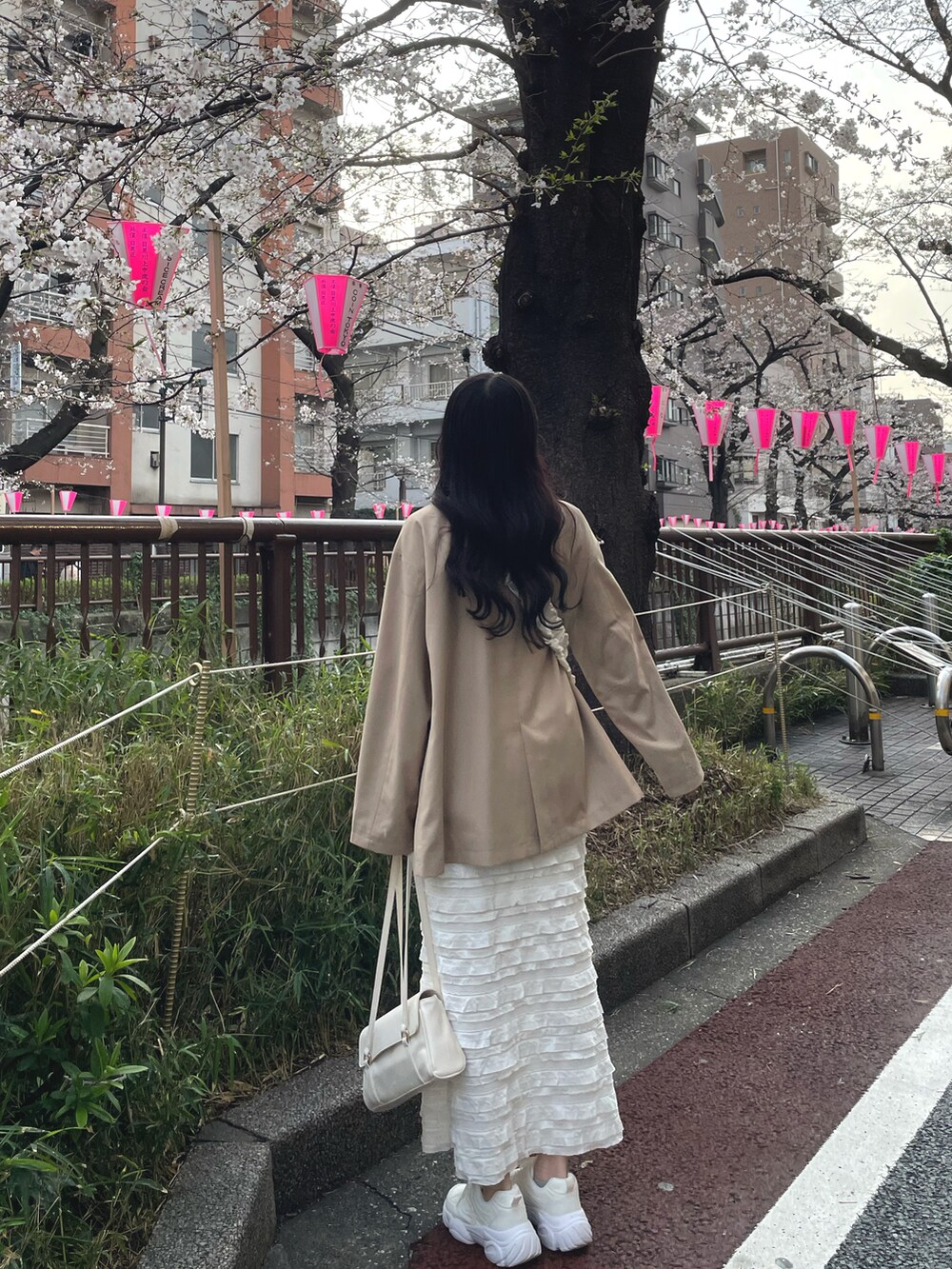 ベージュ系のテーラードジャケット、ホワイト系のスカート、ホワイト系のショルダーバッグを着用したレディースの春コーディネートの4枚目の写真