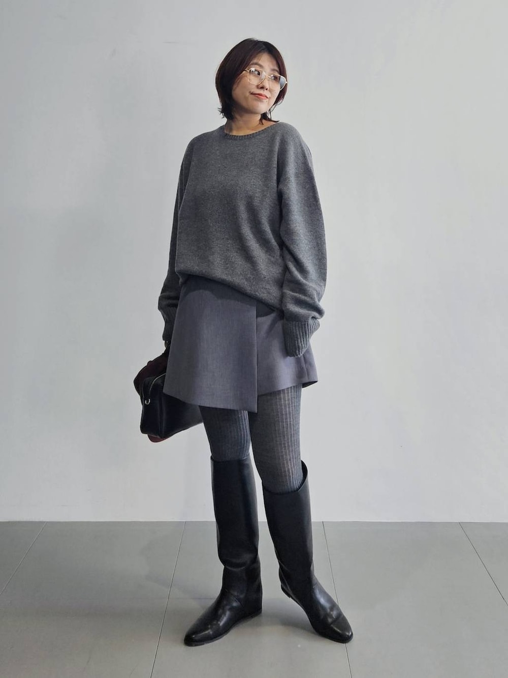 グレー系のニット/セーター、グレー系のその他パンツ、ブラック系のボストンバッグを着用したレディースの秋コーディネートの4枚目の写真