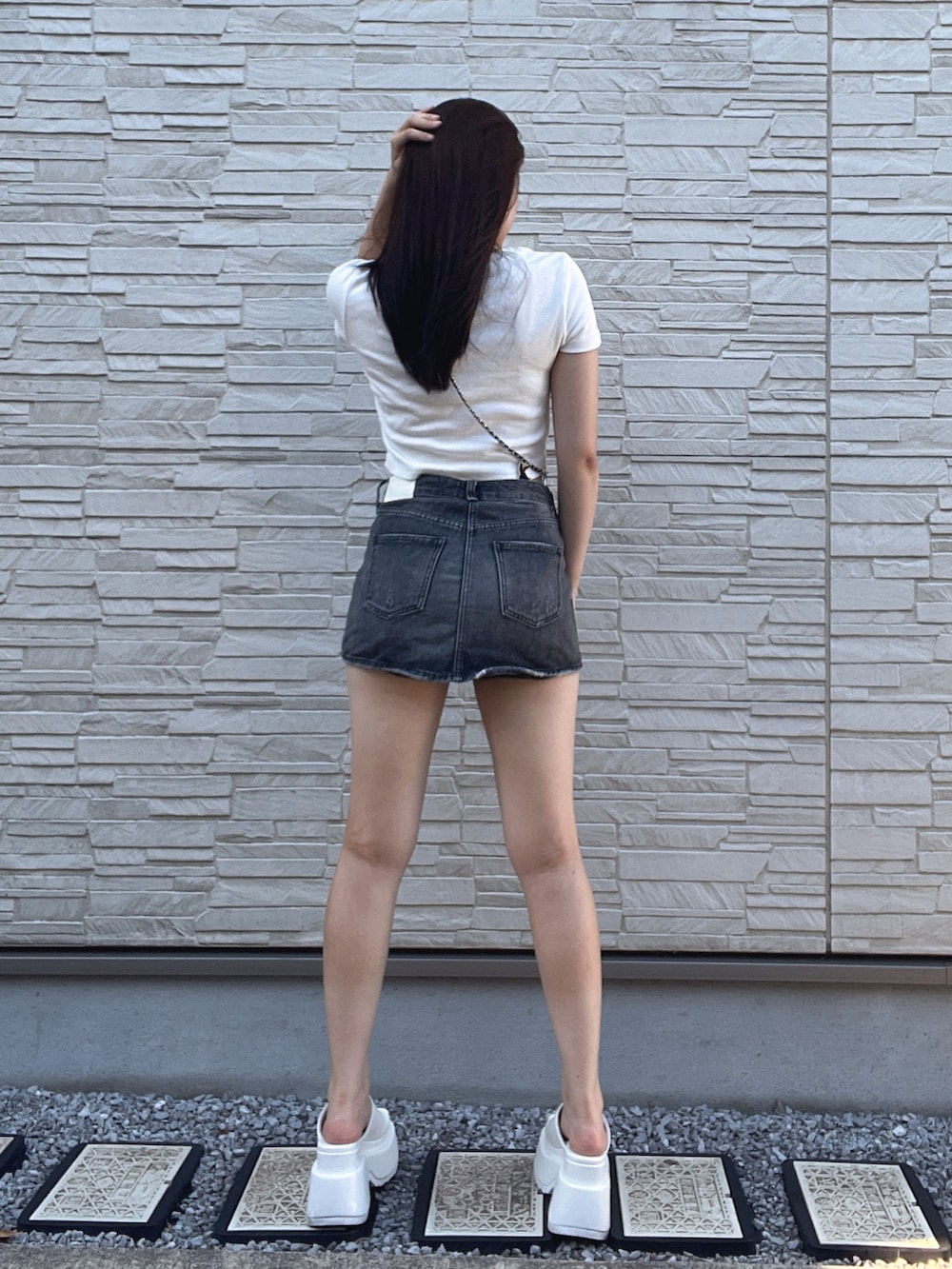 ホワイト系のTシャツ/カットソー、ブラック系のデニムスカート、ホワイト系のサンダルを着用したレディースの夏コーディネートの3枚目の写真