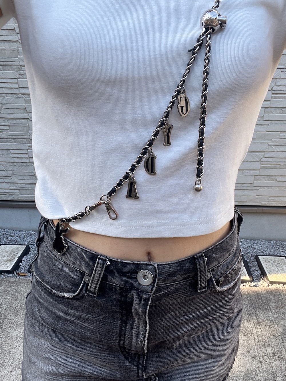 ホワイト系のTシャツ/カットソー、ブラック系のデニムスカート、ホワイト系のサンダルを着用したレディースの夏コーディネートの4枚目の写真