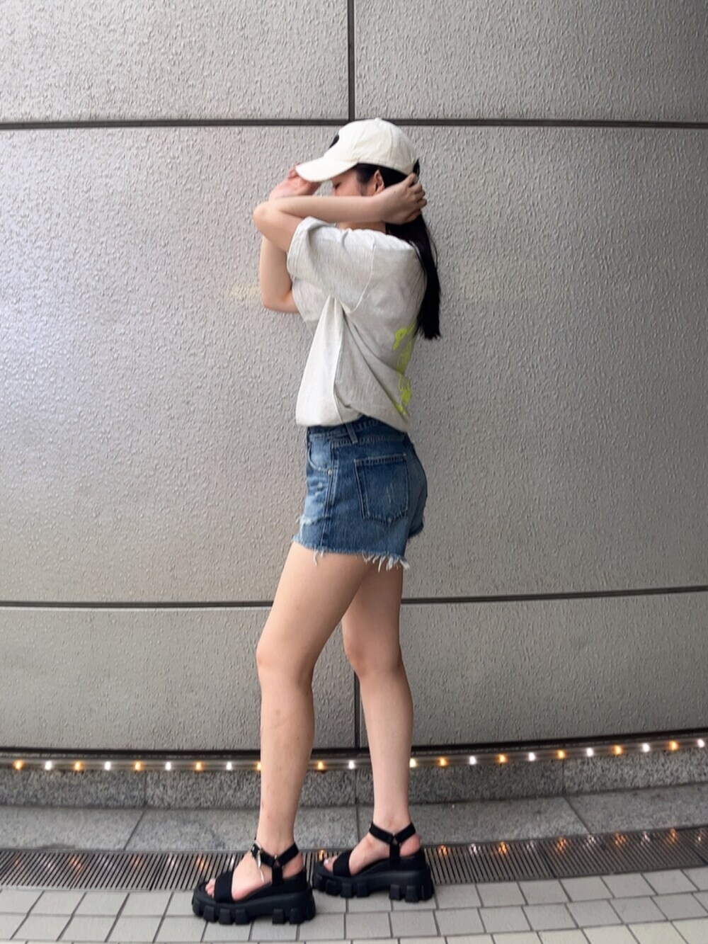 ブルー系のデニムパンツ、グレー系のTシャツ/カットソー、ブラック系のサンダルを着用したレディースの春コーディネートの2枚目の写真