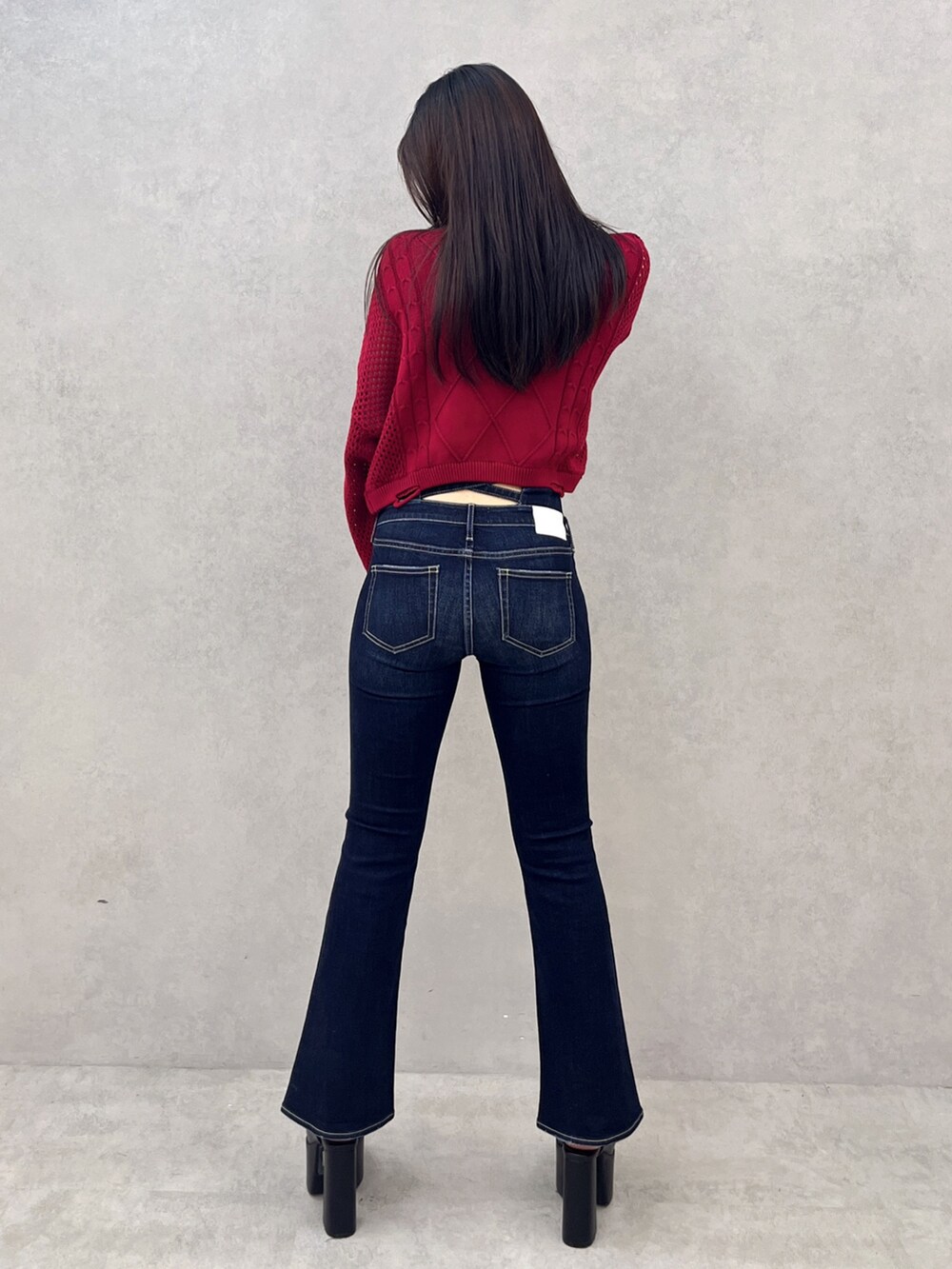 ブルー系のデニムパンツ、ブラック系のサンダル、レッド系のニット/セーターを着用したレディースの夏コーディネートの3枚目の写真