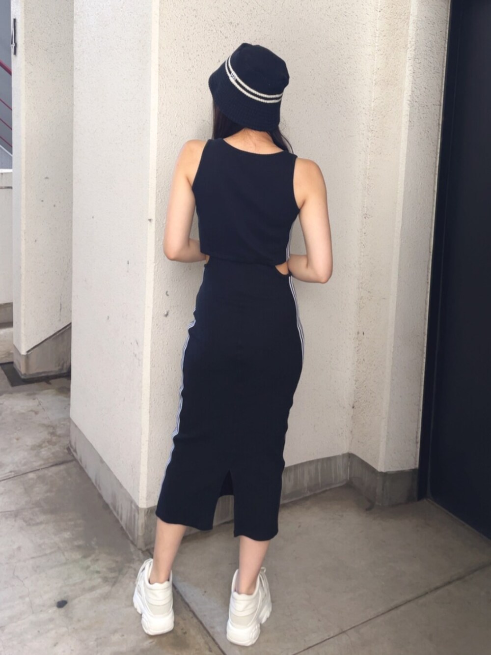 ホワイト系のハンドバッグ、ブラック系のワンピース、ホワイト系のスニーカーを着用したレディースの春コーディネートの3枚目の写真