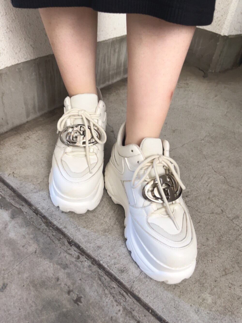 ホワイト系のハンドバッグ、ブラック系のワンピース、ホワイト系のスニーカーを着用したレディースの春コーディネートの4枚目の写真