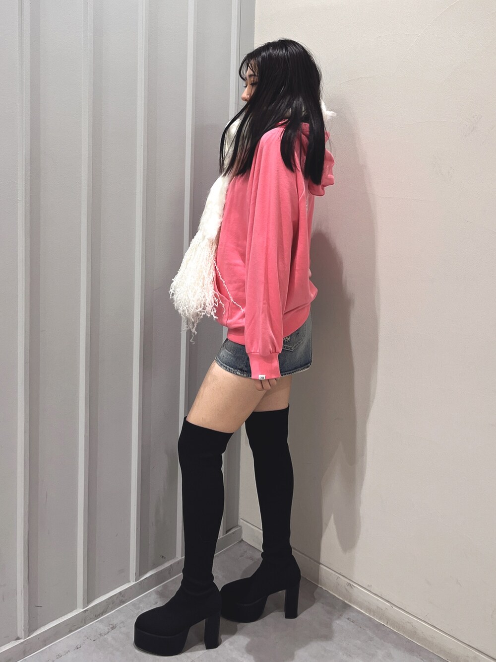 ブラック系のデニムスカート、ブラック系のブーツ、ピンク系のパーカーを着用したレディースの冬コーディネートの2枚目の写真