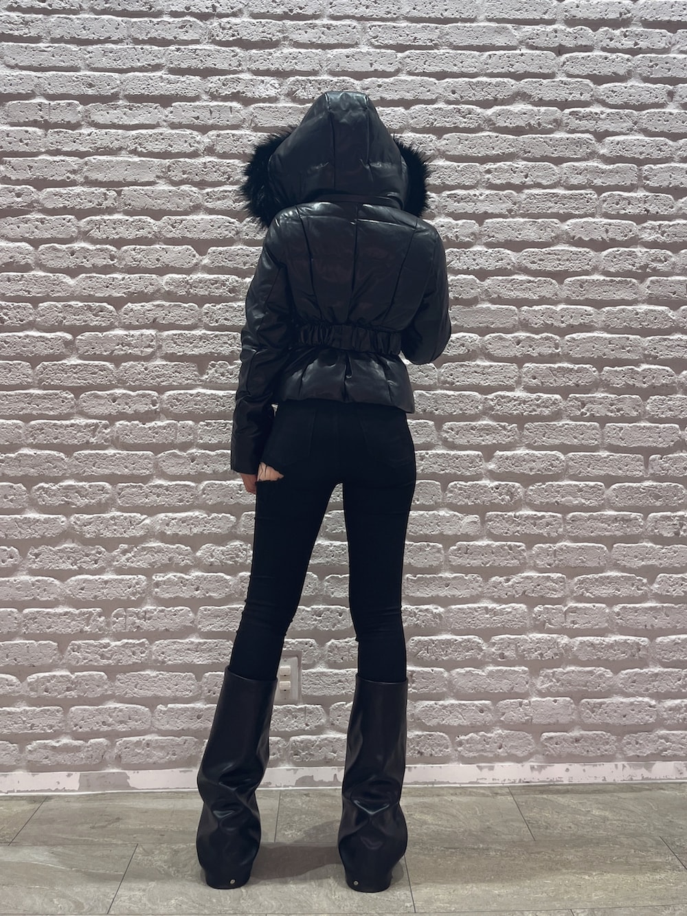 ブラック系のデニムパンツ、ブラック系のダウンジャケット/コート、ブラック系のブーツを着用したレディースの秋コーディネートの3枚目の写真