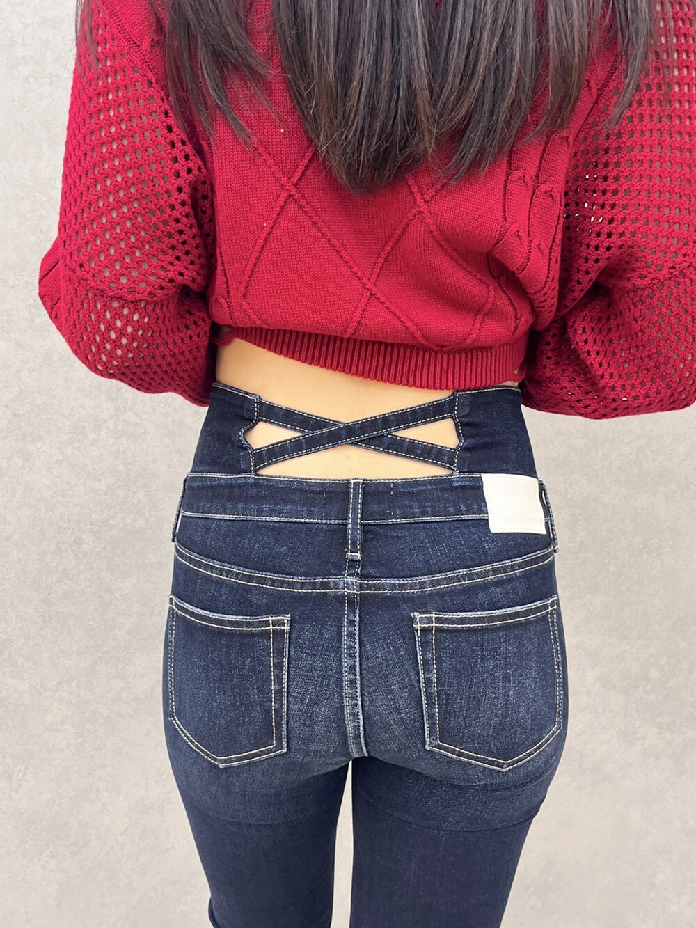 ブルー系のデニムパンツ、ブラック系のサンダル、レッド系のニット/セーターを着用したレディースの夏コーディネートの5枚目の写真