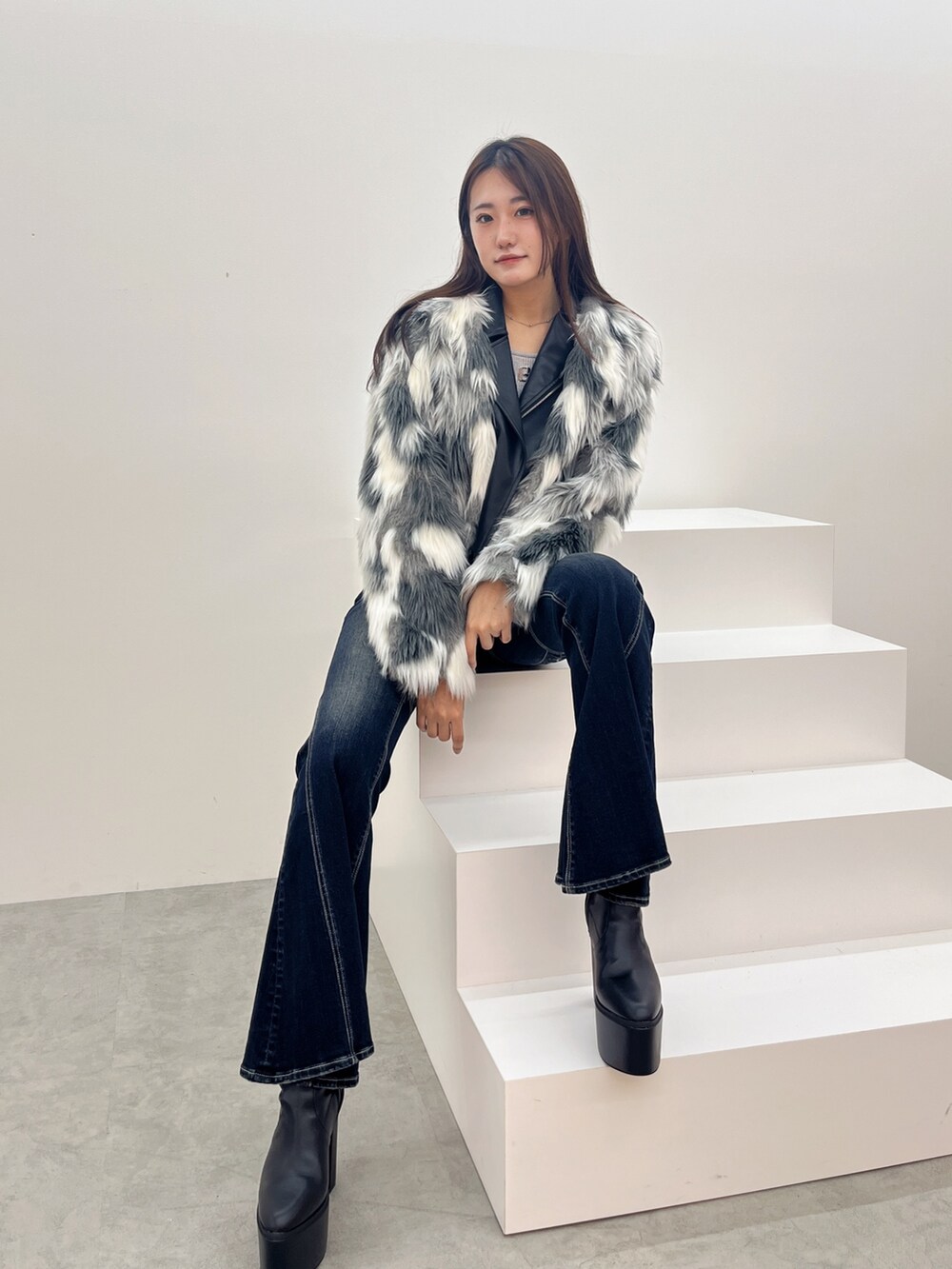 ブラック系のブーツ、シルバー系のニット/セーター、ブルー系のデニムパンツを着用したレディースの秋コーディネートの4枚目の写真