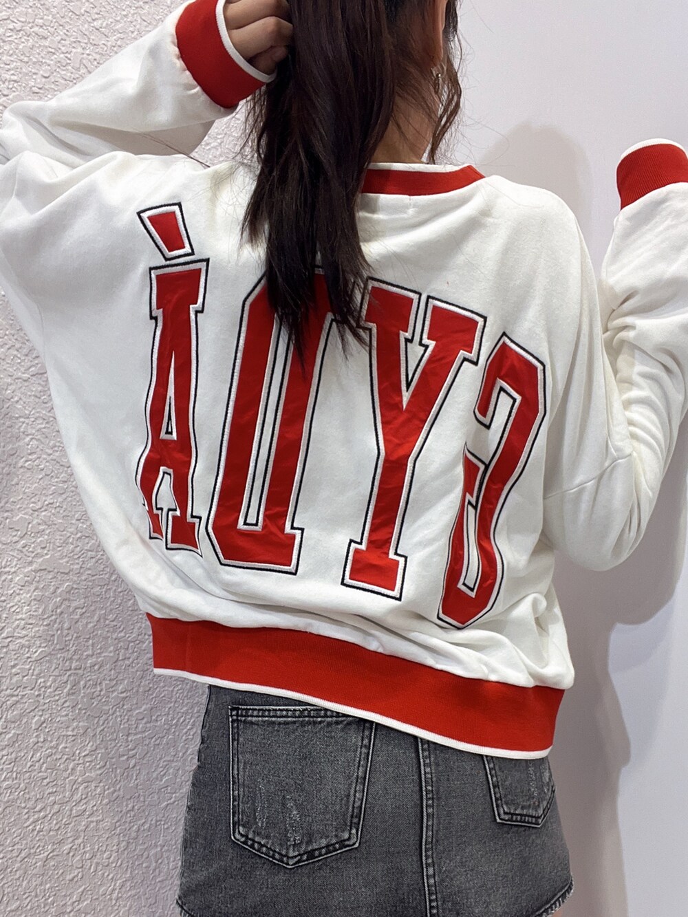 ホワイト系のスウェット、ブラック系のデニムスカート、ブラック系のブーツを着用したレディースの夏コーディネートの4枚目の写真