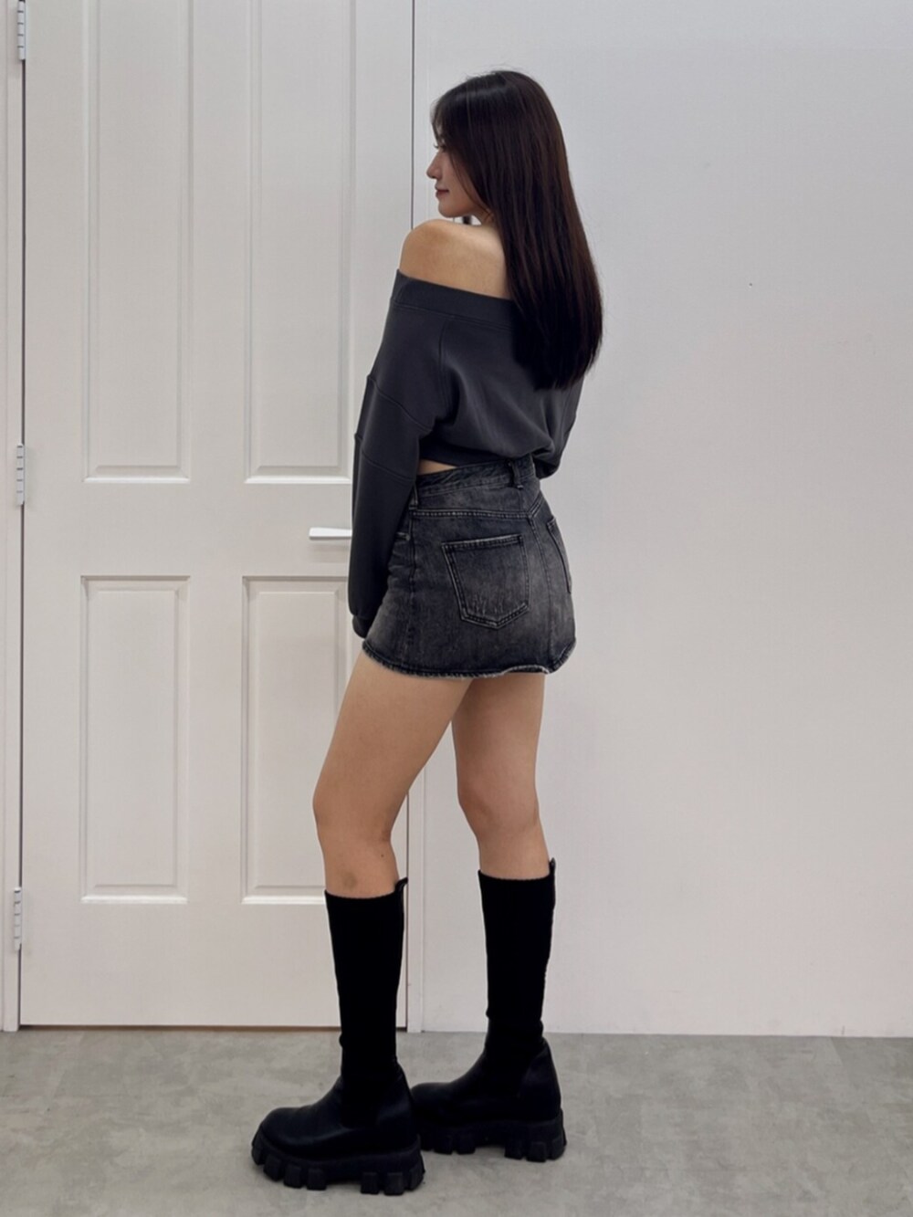 ブラック系のブーツ、ブラック系のデニムスカート、グレー系のTシャツ/カットソーを着用したレディースの秋コーディネートの2枚目の写真