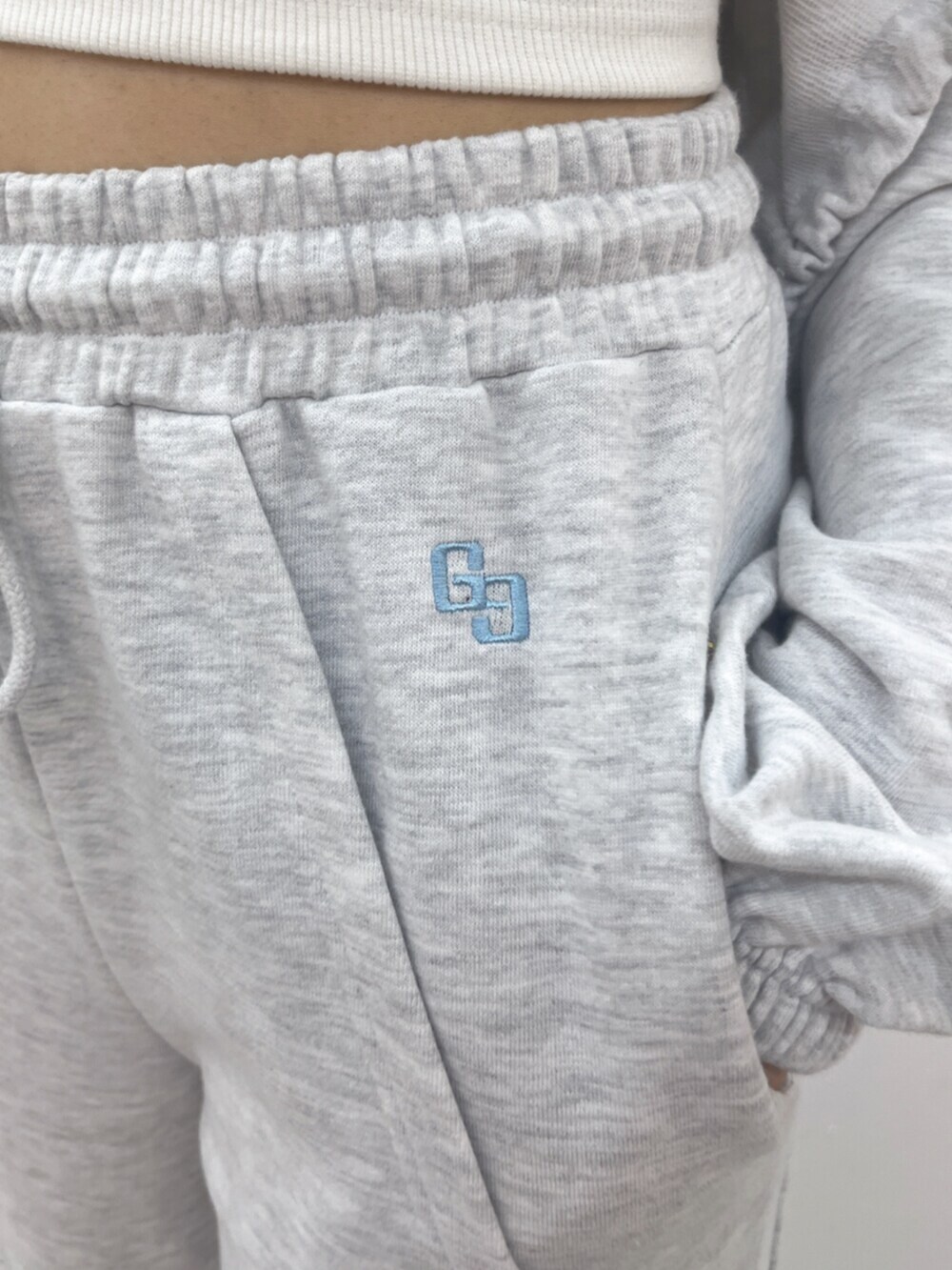 ホワイト系のキャミソール、グレー系のパーカー、グレー系のスウェットパンツを着用したレディースの春コーディネートの5枚目の写真