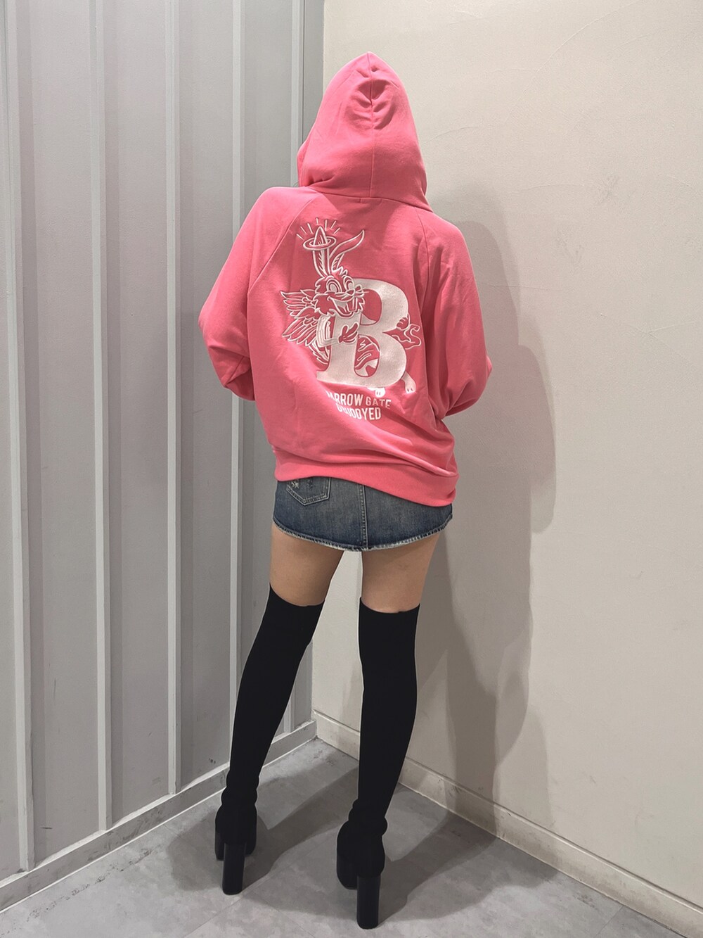 ブラック系のデニムスカート、ブラック系のブーツ、ピンク系のパーカーを着用したレディースの冬コーディネートの3枚目の写真