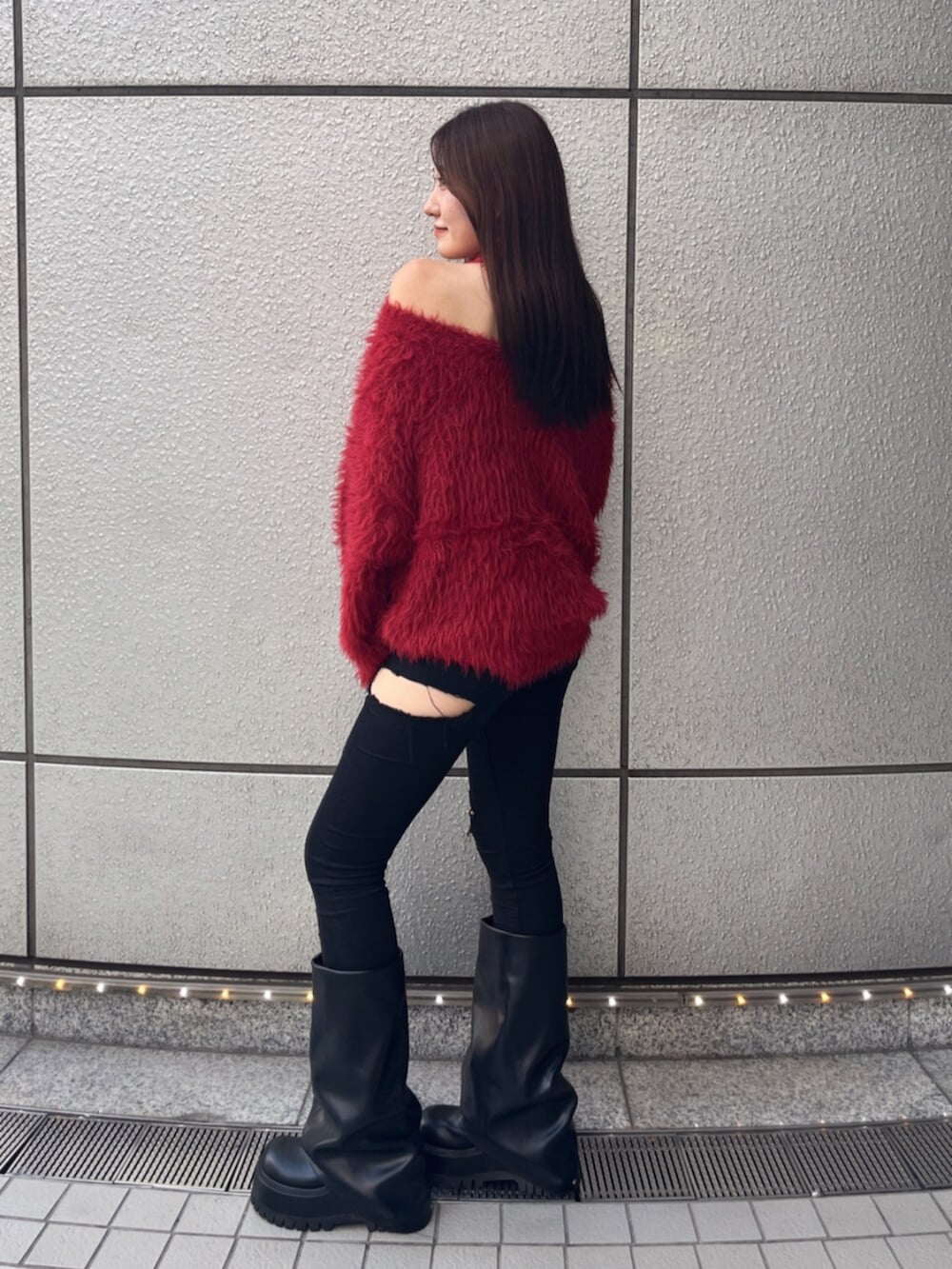 ブラック系のデニムパンツ、ブラック系のブーツ、レッド系のニット/セーターを着用したレディースの秋コーディネートの2枚目の写真