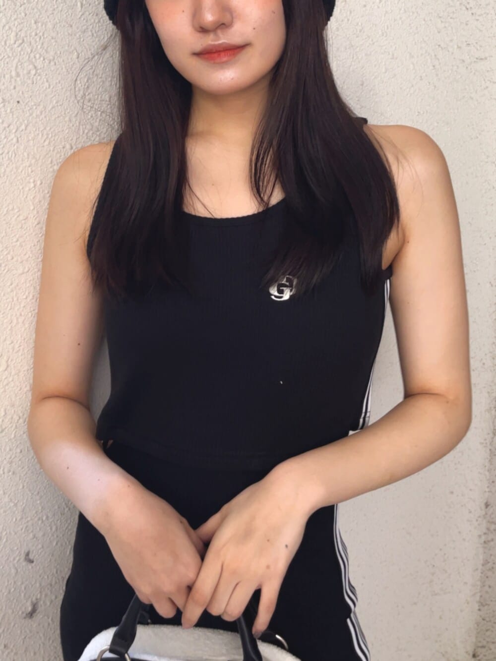 ホワイト系のハンドバッグ、ブラック系のワンピース、ホワイト系のスニーカーを着用したレディースの春コーディネートの6枚目の写真