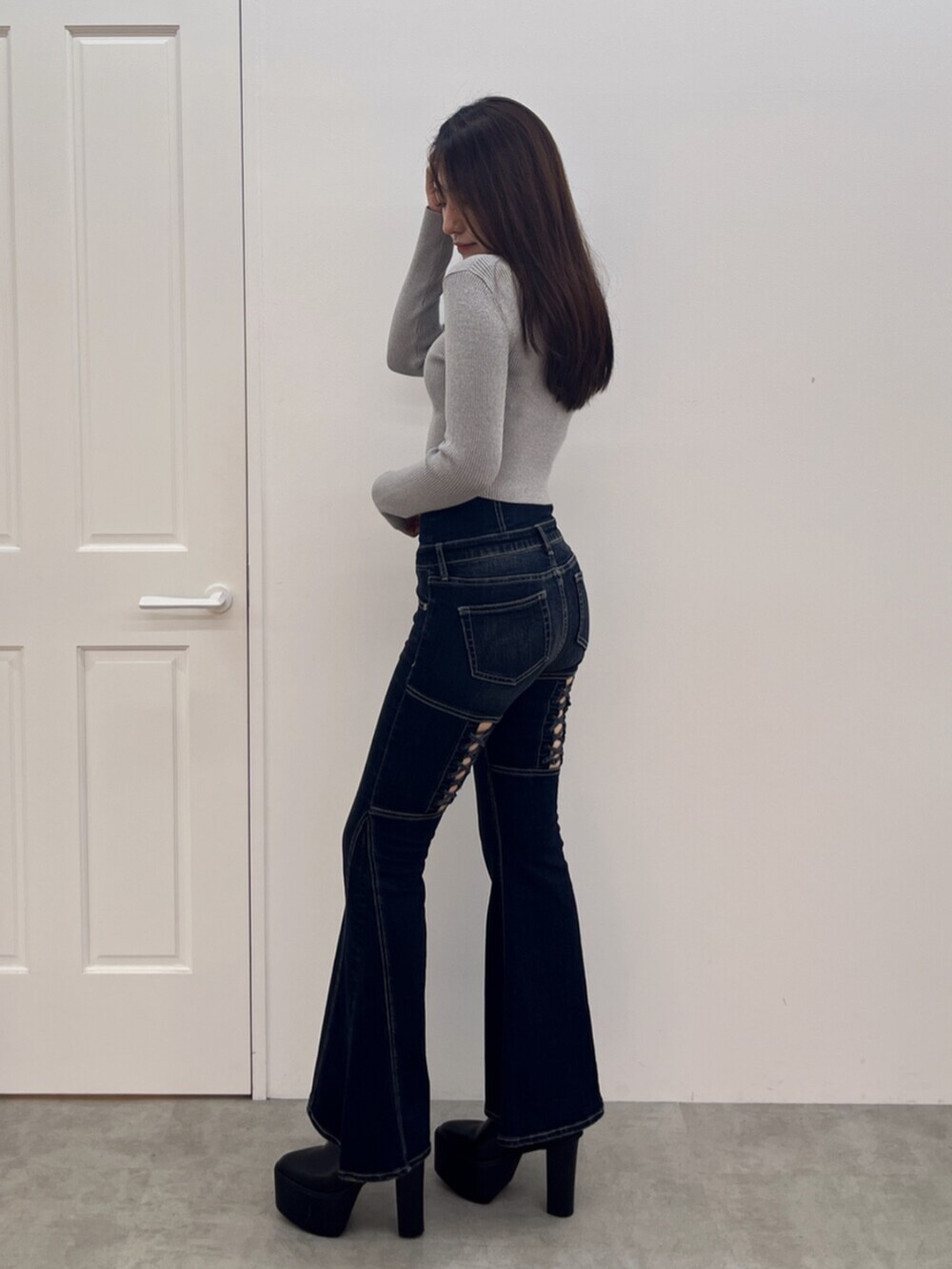 ブラック系のブーツ、シルバー系のニット/セーター、ブルー系のデニムパンツを着用したレディースの秋コーディネートの2枚目の写真