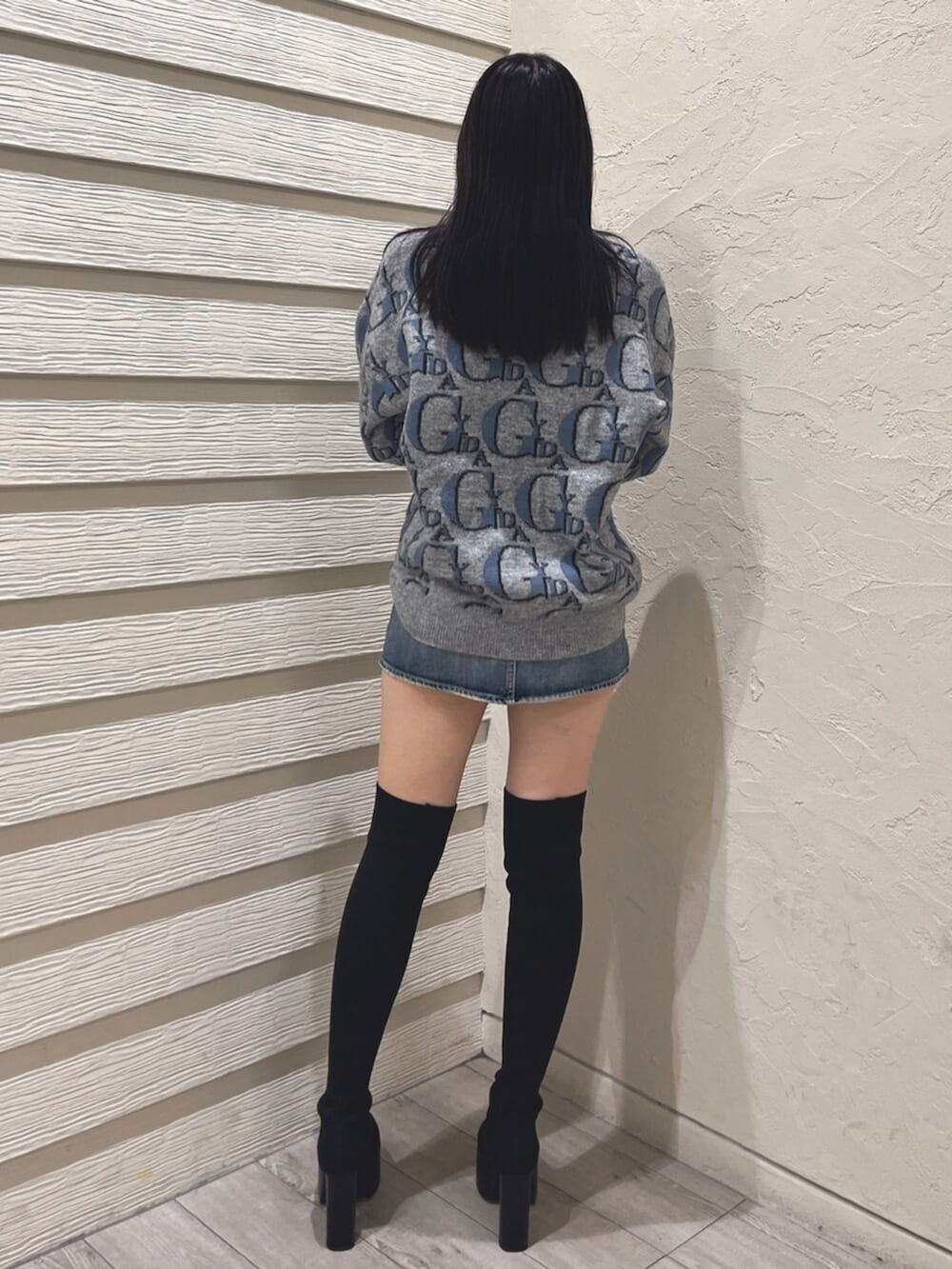 ブラック系のブーツ、グレー系のニット/セーター、ブルー系のデニムスカートを着用したレディースの冬コーディネートの3枚目の写真