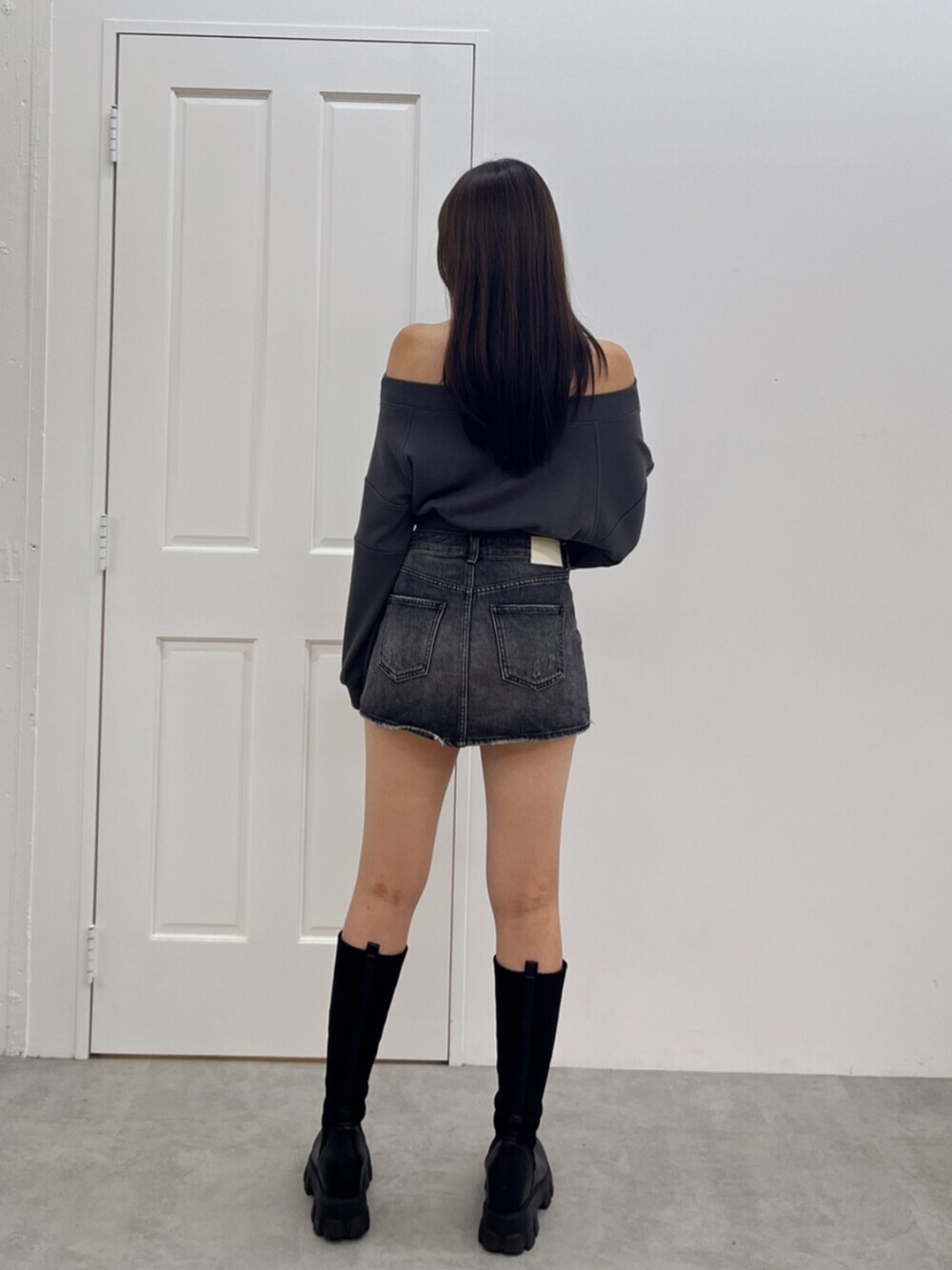 ブラック系のブーツ、ブラック系のデニムスカート、グレー系のTシャツ/カットソーを着用したレディースの秋コーディネートの3枚目の写真