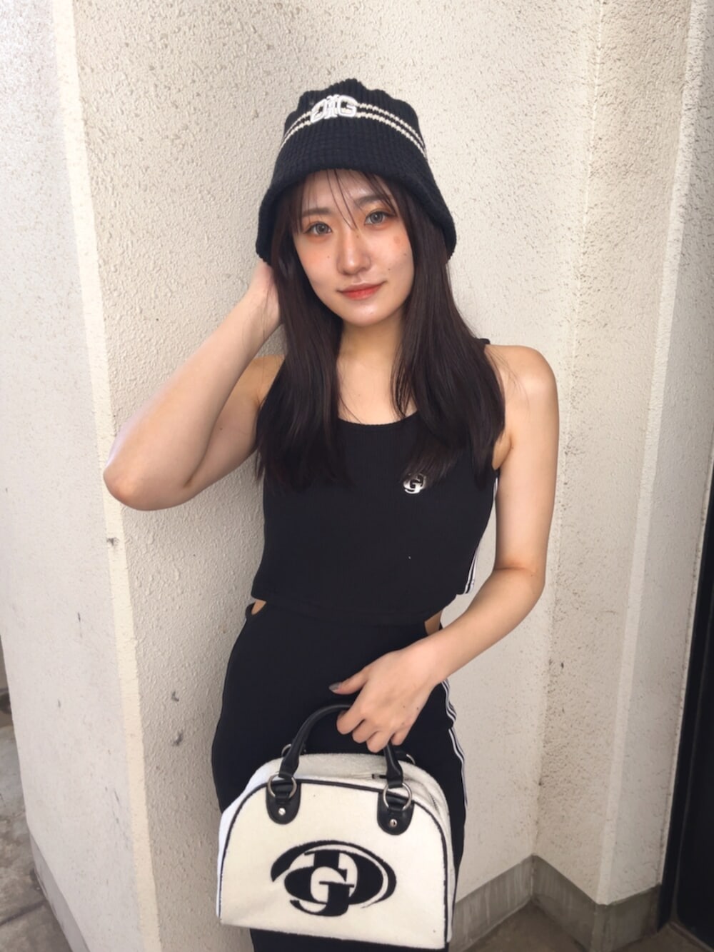 ホワイト系のハンドバッグ、ブラック系のワンピース、ホワイト系のスニーカーを着用したレディースの春コーディネートの7枚目の写真