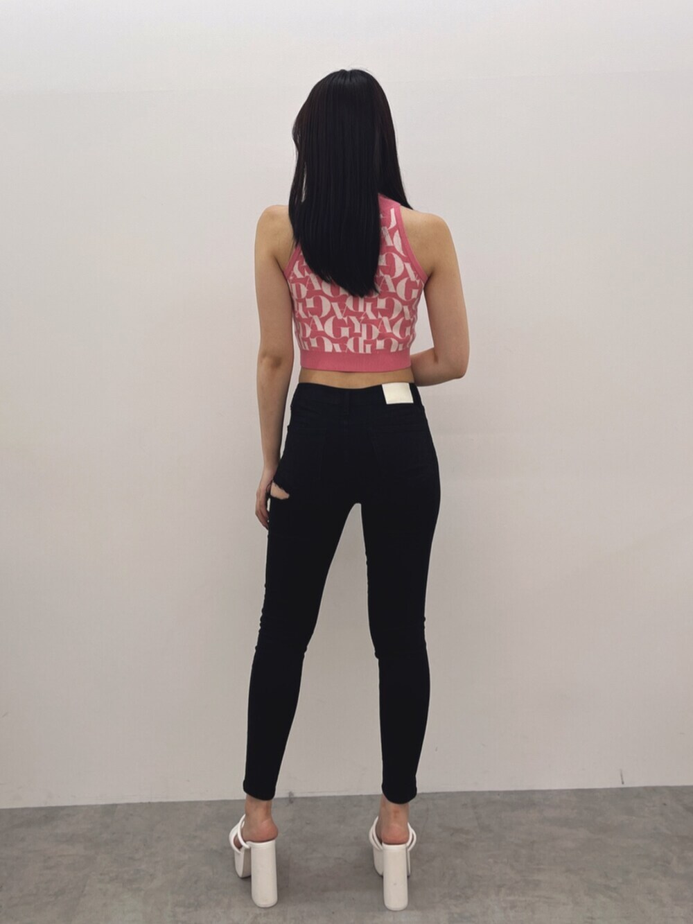 ブラック系のデニムパンツ、ピンク系のニット/セーター、ホワイト系のサンダルを着用したレディースの春コーディネートの3枚目の写真