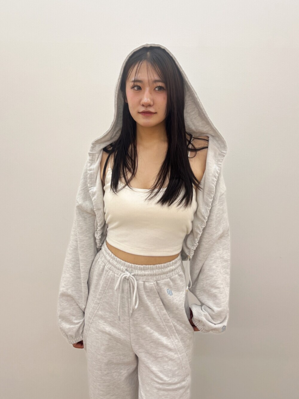 ホワイト系のキャミソール、グレー系のパーカー、グレー系のスウェットパンツを着用したレディースの春コーディネートの4枚目の写真