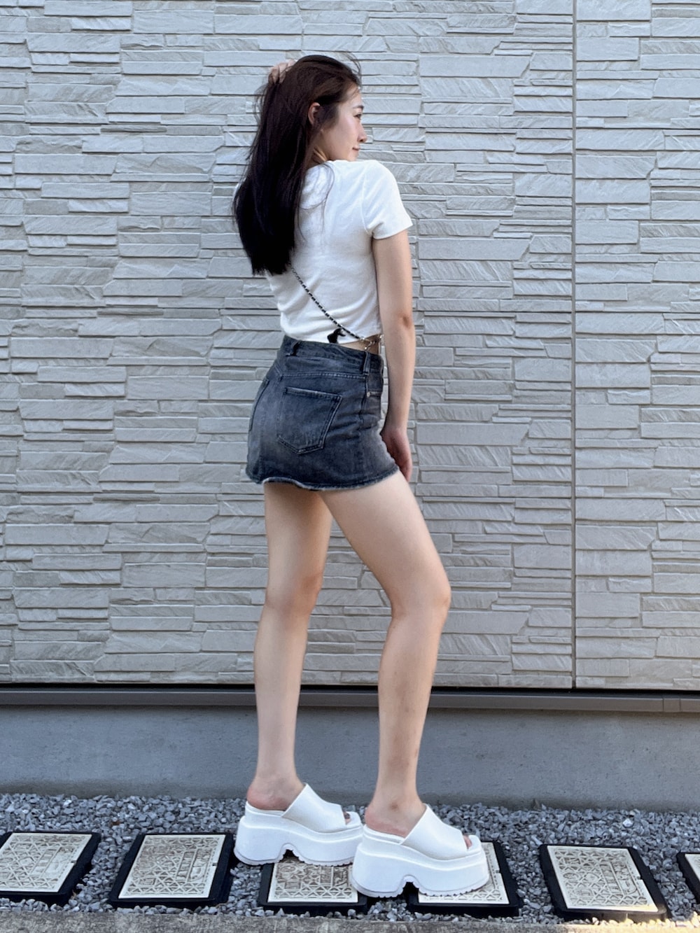 ホワイト系のTシャツ/カットソー、ブラック系のデニムスカート、ホワイト系のサンダルを着用したレディースの夏コーディネートの2枚目の写真