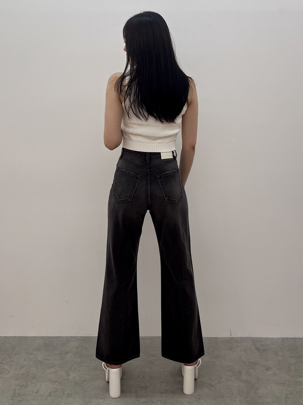 ブラック系のデニムパンツ、ホワイト系のニット/セーター、ホワイト系のサンダルを着用したレディースの夏コーディネートの4枚目の写真