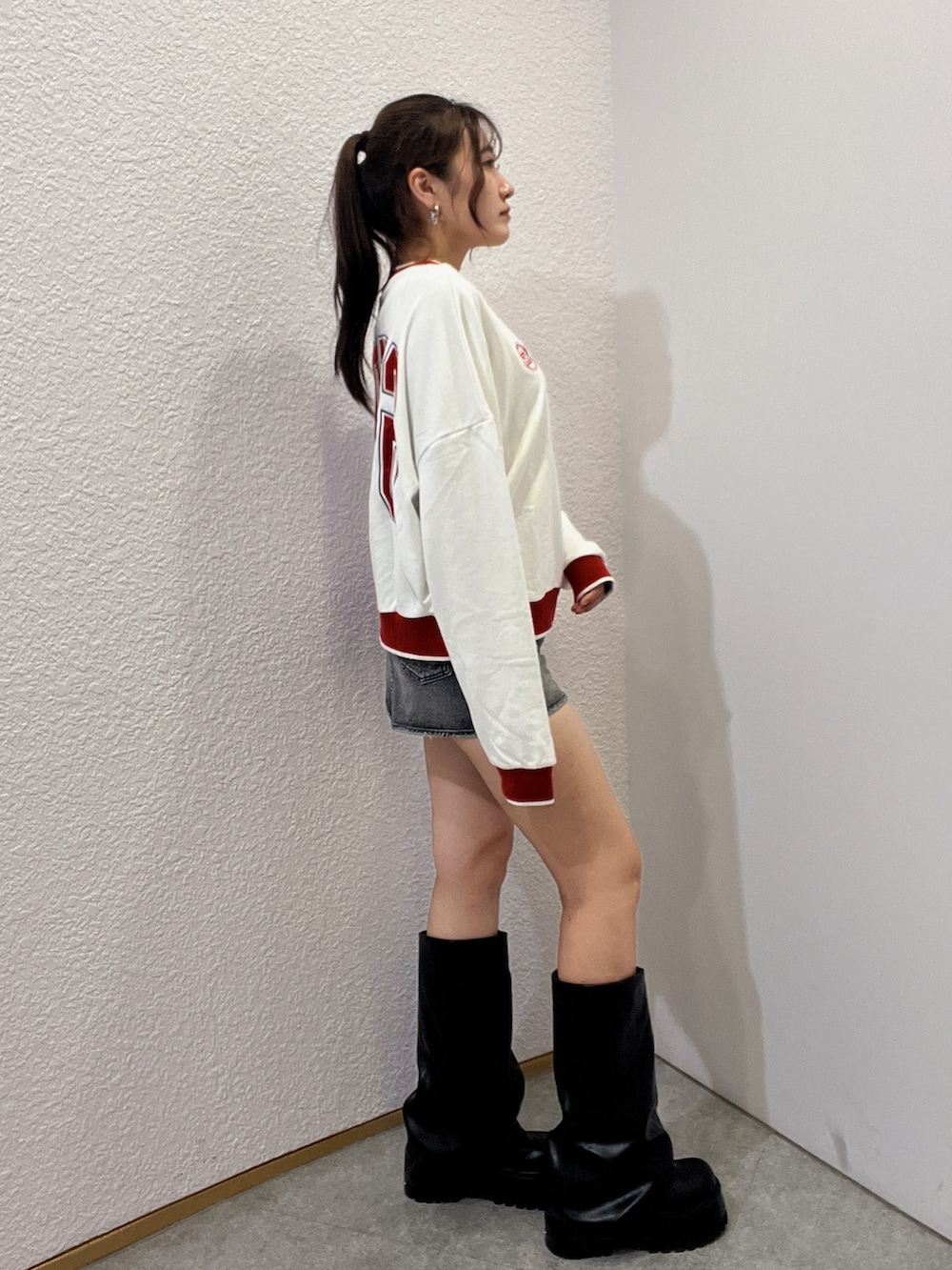 ホワイト系のスウェット、ブラック系のデニムスカート、ブラック系のブーツを着用したレディースの夏コーディネートの2枚目の写真