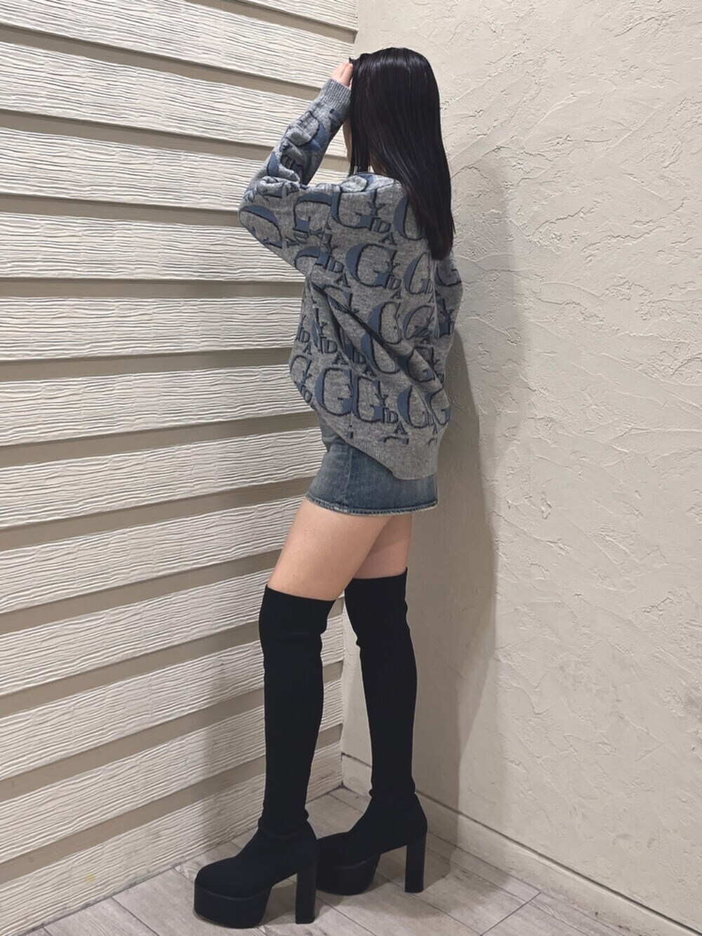 ブラック系のブーツ、グレー系のニット/セーター、ブルー系のデニムスカートを着用したレディースの冬コーディネートの2枚目の写真