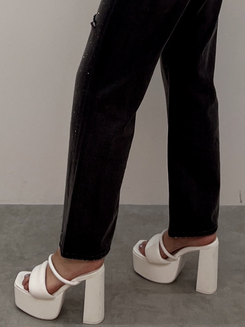 ブラック系のデニムパンツ、ホワイト系のニット/セーター、ホワイト系のサンダルを着用したレディースの夏コーディネートの3枚目の写真