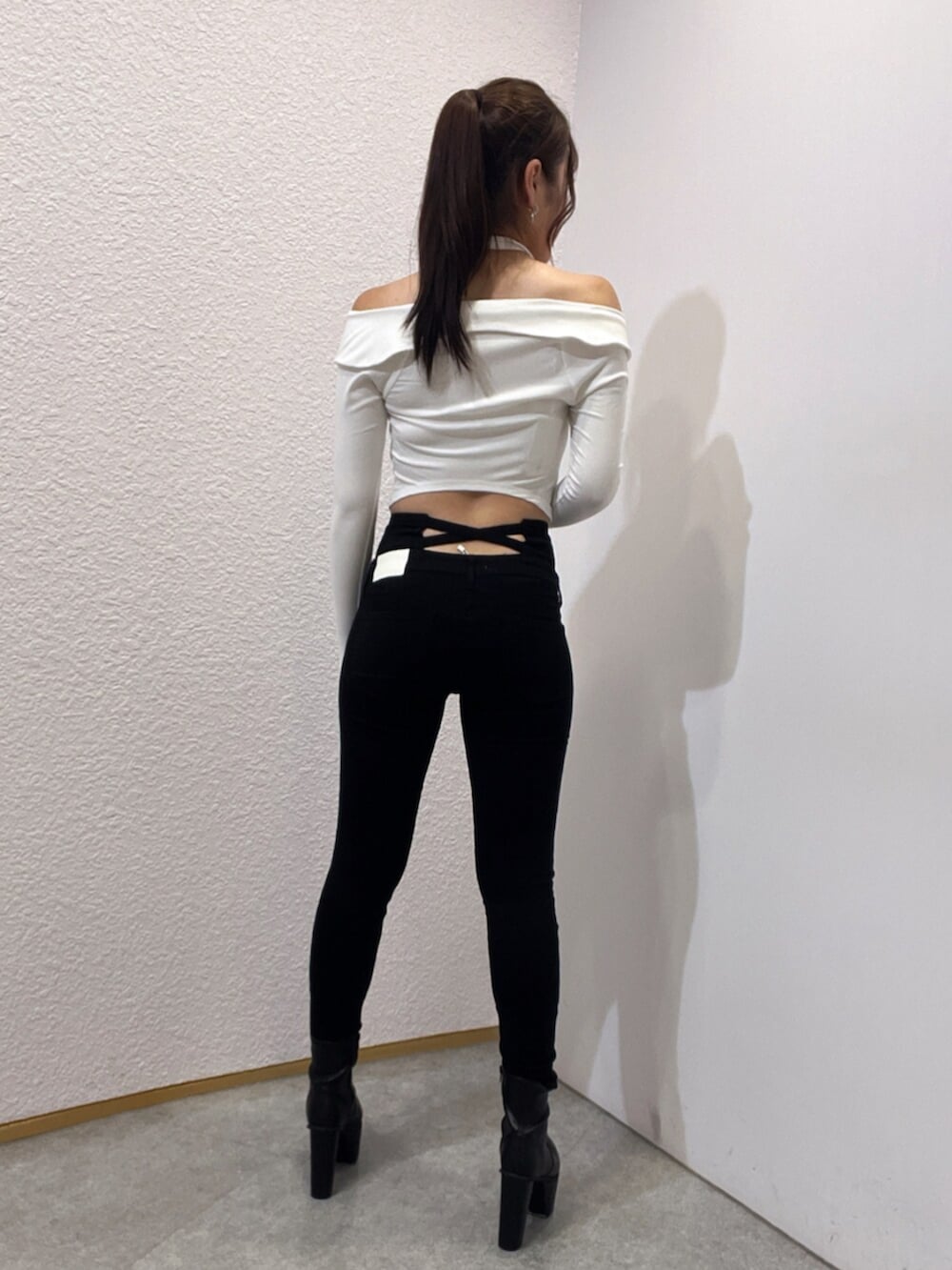 ブラック系のデニムパンツ、ブラック系のブーツ、ホワイト系のTシャツ/カットソーを着用したレディースの夏コーディネートの3枚目の写真