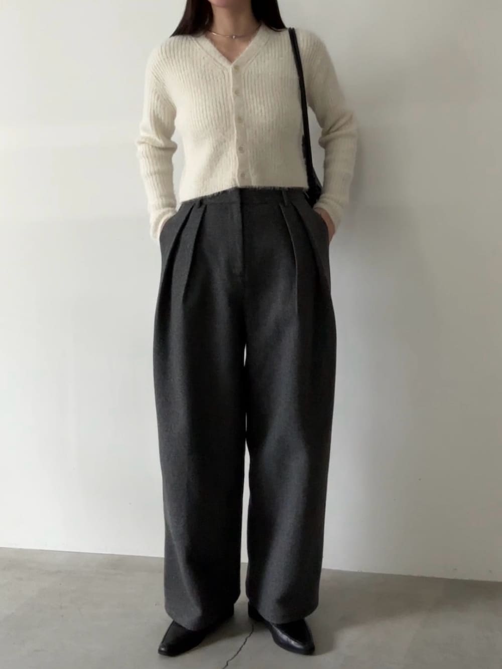 グレー系のスラックス、ホワイト系のカーディガン/ボレロを着用したレディースの冬コーディネートの2枚目の写真