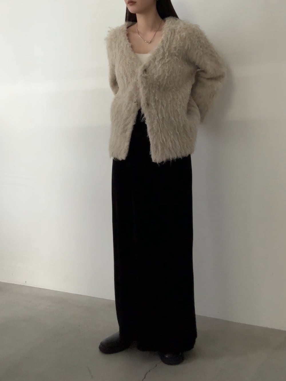 ブラック系のスカート、ベージュ系のカーディガン/ボレロ、ホワイト系のキャミソールを着用したレディースの冬コーディネートの2枚目の写真