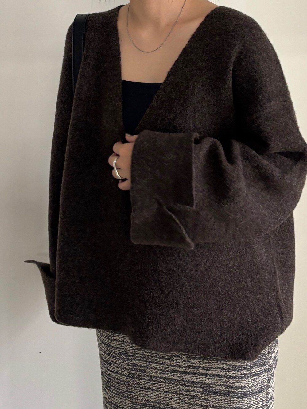 ブラック系のブーツ、グレー系のスカート、ブラウン系のニット/セーターを着用したレディースの秋コーディネートの2枚目の写真