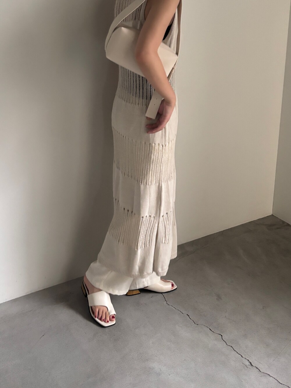 ベージュ系のワンピース、ホワイト系のショルダーバッグ、ホワイト系のスラックスを着用したレディースの夏コーディネートの2枚目の写真