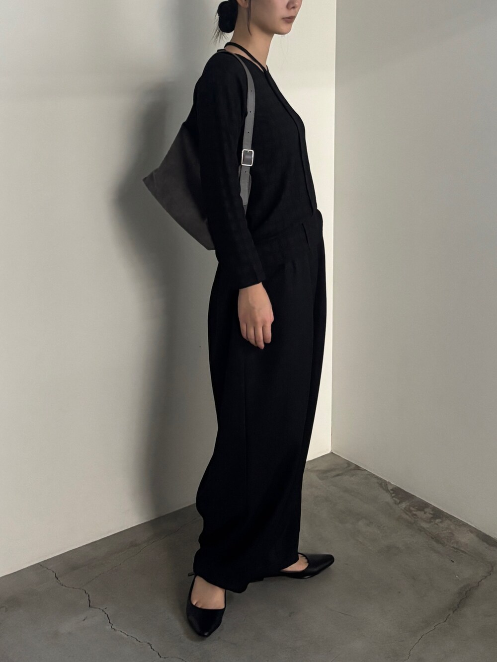 グレー系のスラックス、ブラック系のTシャツ/カットソー、ブラック系のサンダルを着用したレディースの夏コーディネートの2枚目の写真